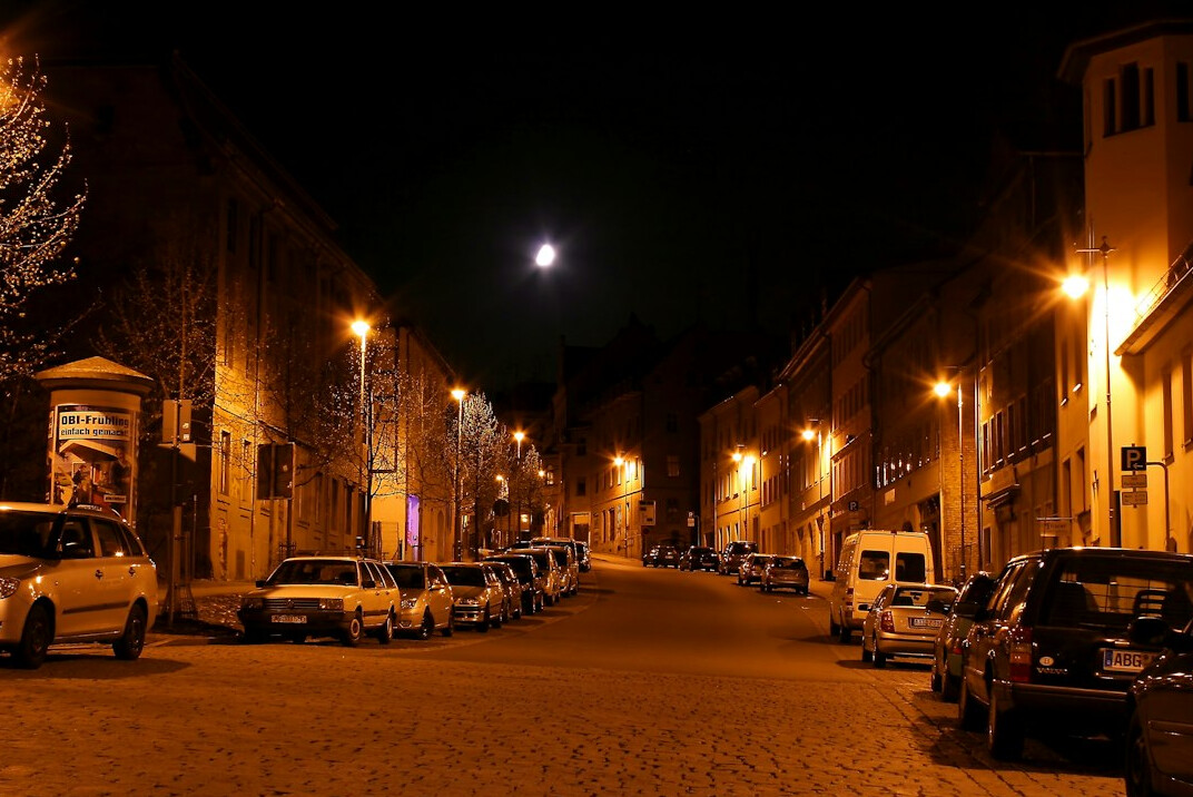 Empty cobblestone street at night under a full moon