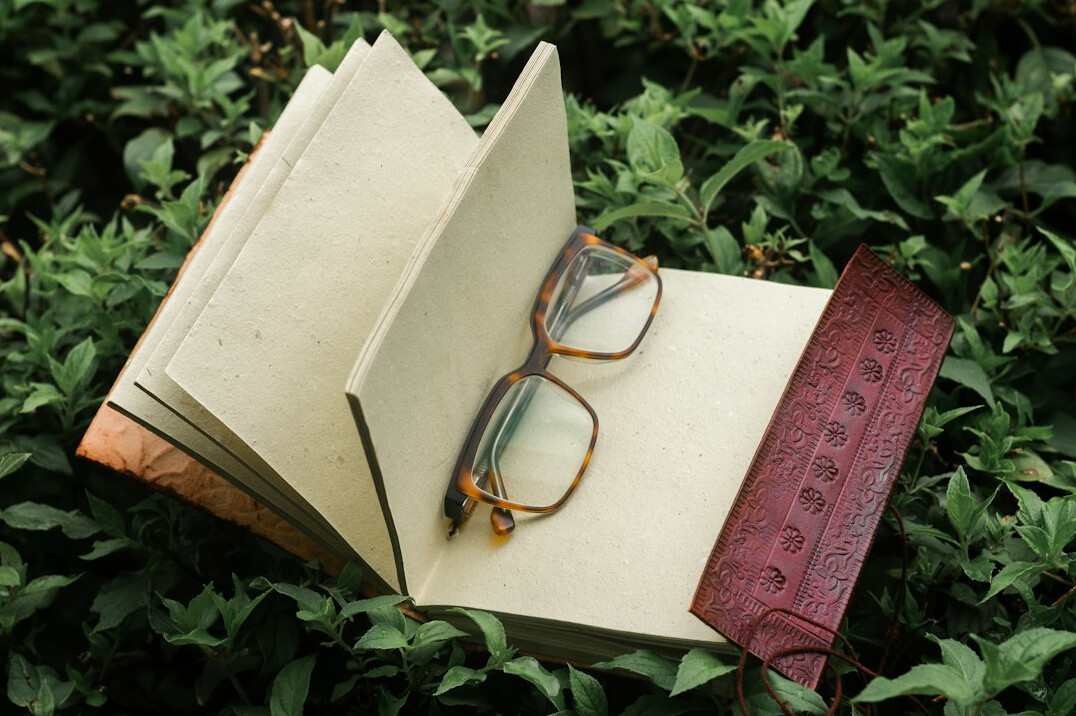 Open notebook with magnifying glass and pen on a wooden desk