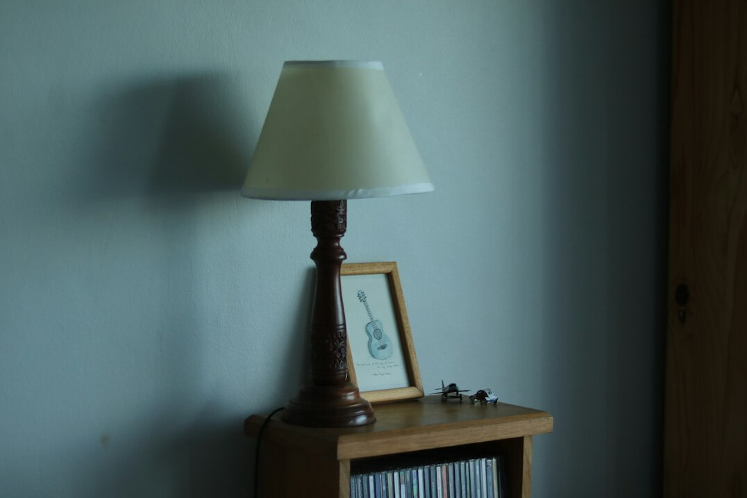 Old case files spread on a wooden table with a lamp